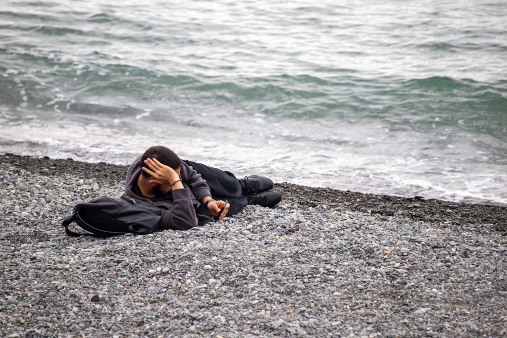 man laying on rocky beach looking down