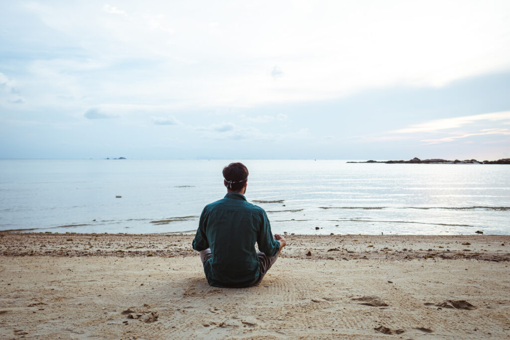 man meditating on beach